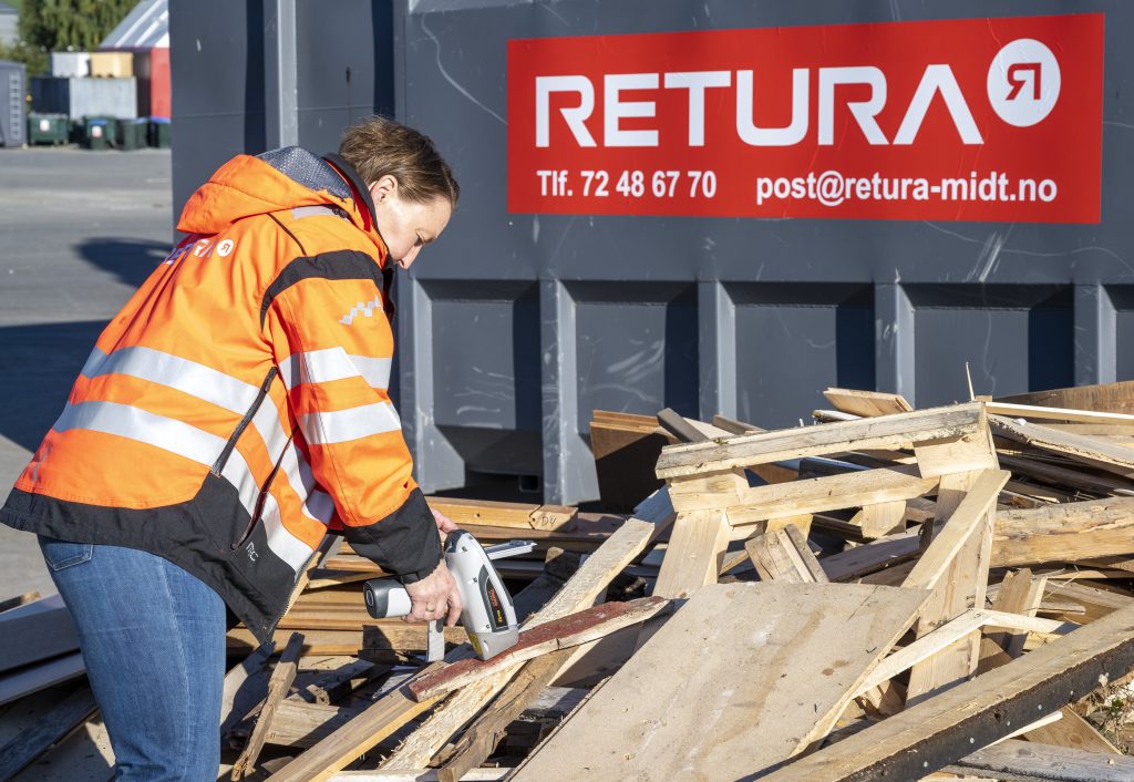 dame i oransje jakke med refleks tester trevirke med eget verktøy